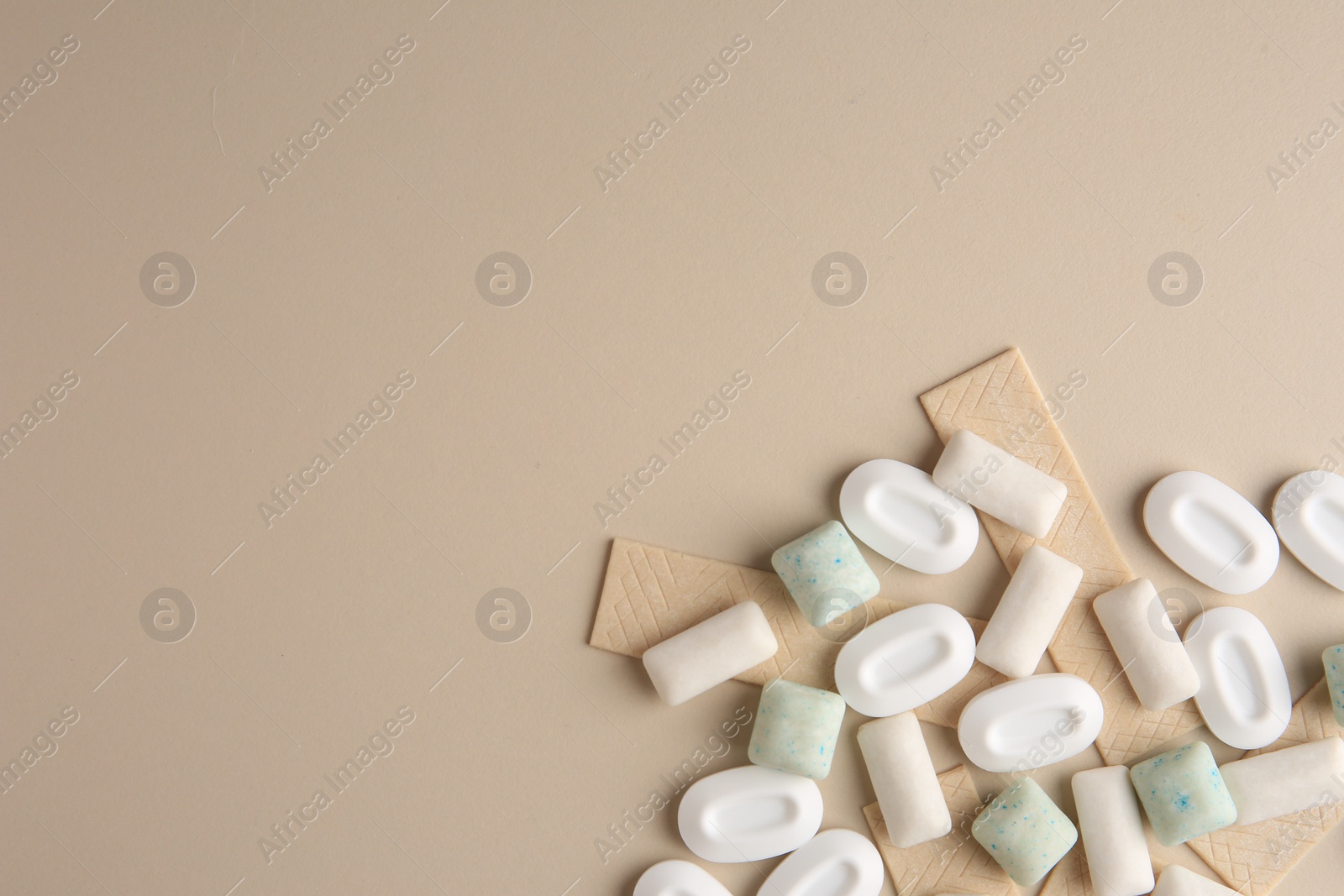 Photo of Many different chewing gums on beige background, flat lay. Space for text