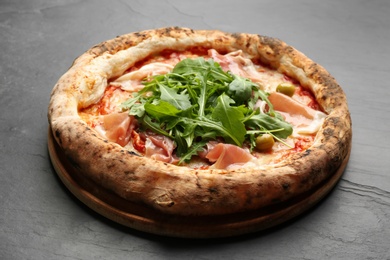 Photo of Tasty pizza with meat and arugula on black table, closeup
