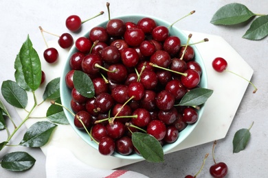 Photo of Sweet juicy cherries and leaves on grey table, flat lay