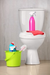 Different cleaning supplies and toilet bowl indoors