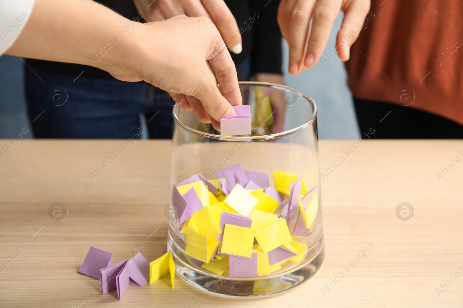 Photo of Women playing lottery, focus on hands and glass vase with paper pieces