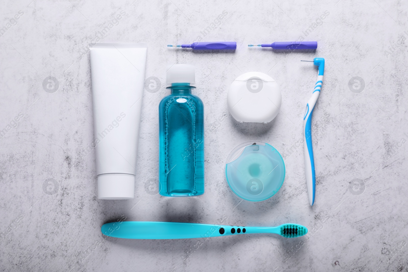 Photo of Flat lay composition with dental floss and different teeth care products on light grey textured table