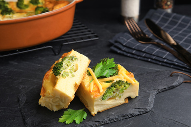 Photo of Tasty broccoli casserole served on black table