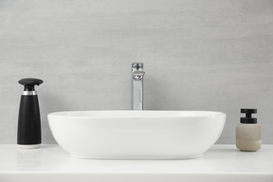 Photo of Modern automatic soap dispenser near sink in bathroom