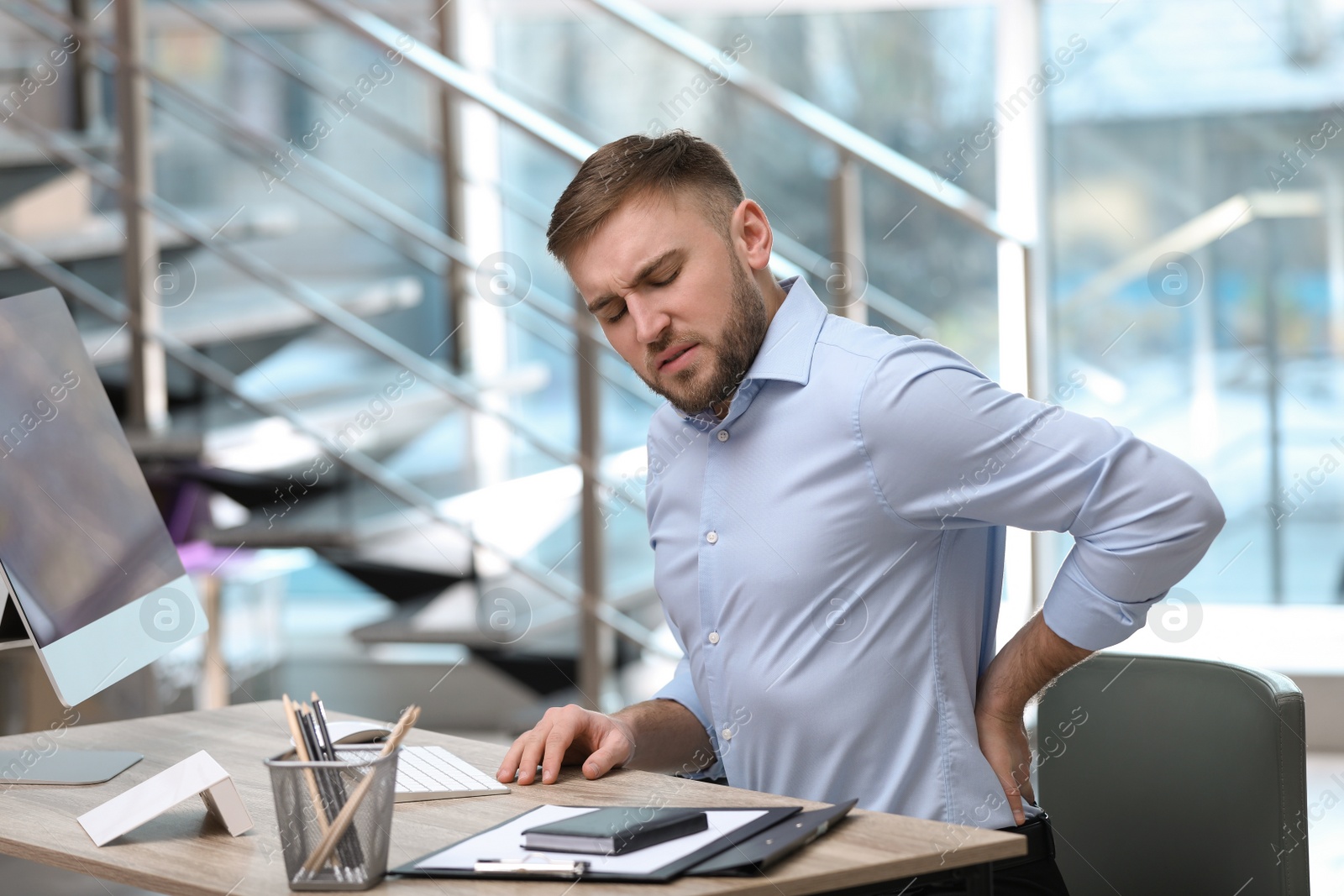 Photo of Businessman suffering from back pain at workplace