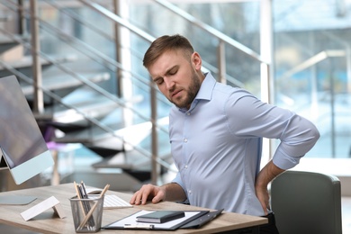 Businessman suffering from back pain at workplace