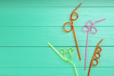 Photo of Colorful plastic drinking straws on turquoise wooden table, flat lay. Space for text