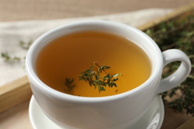 Cup of fresh thyme tea on table, closeup