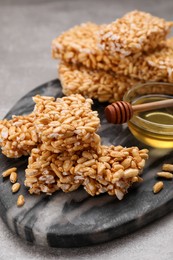 Photo of Board with puffed rice bars (kozinaki) on grey table, closeup