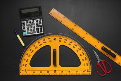 Photo of Flat lay composition with protractor and ruler on black table