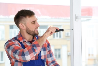 Construction worker adjusting installed window with screwdriver indoors