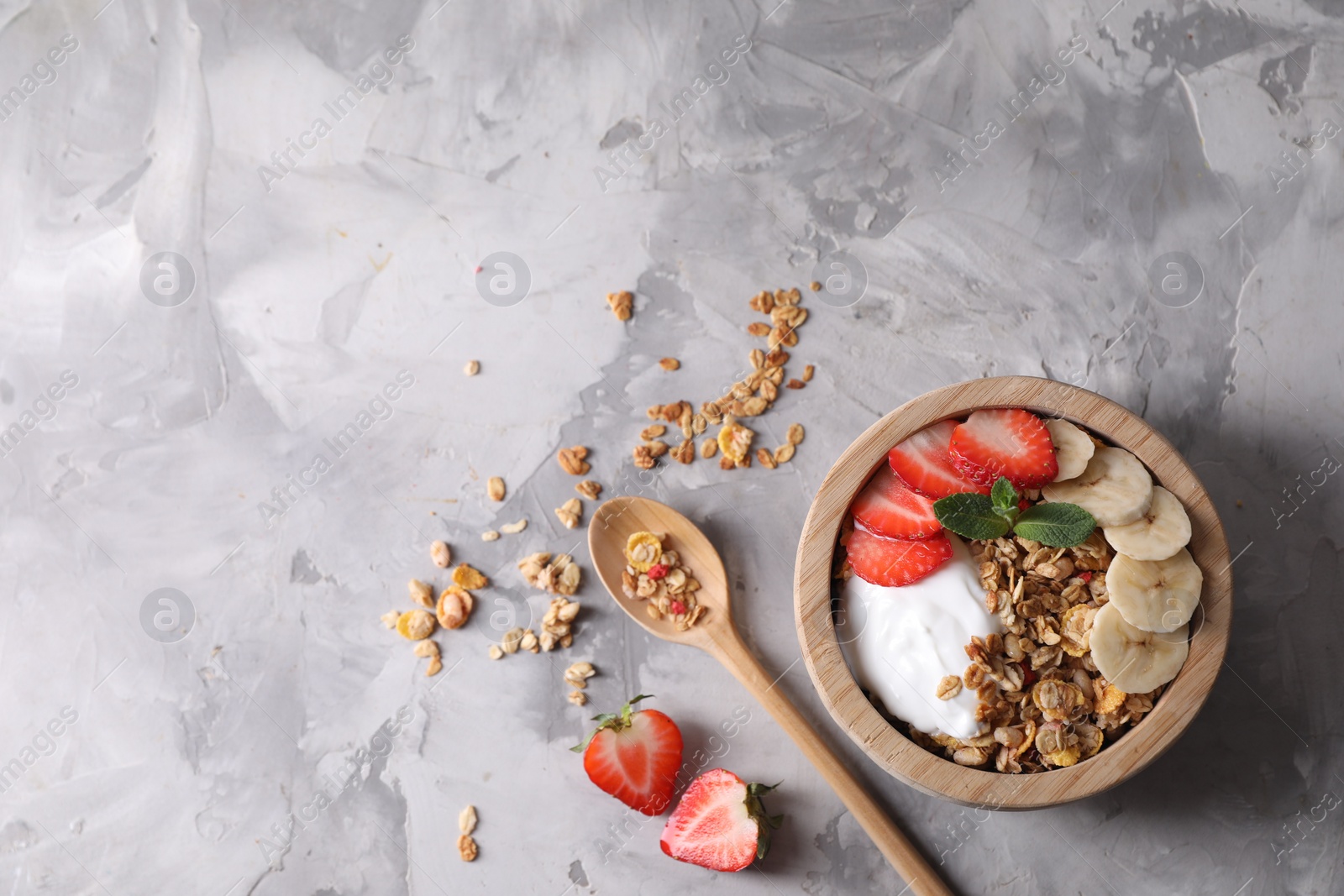 Photo of Tasty granola served on gray textured table, flat lay. Space for text