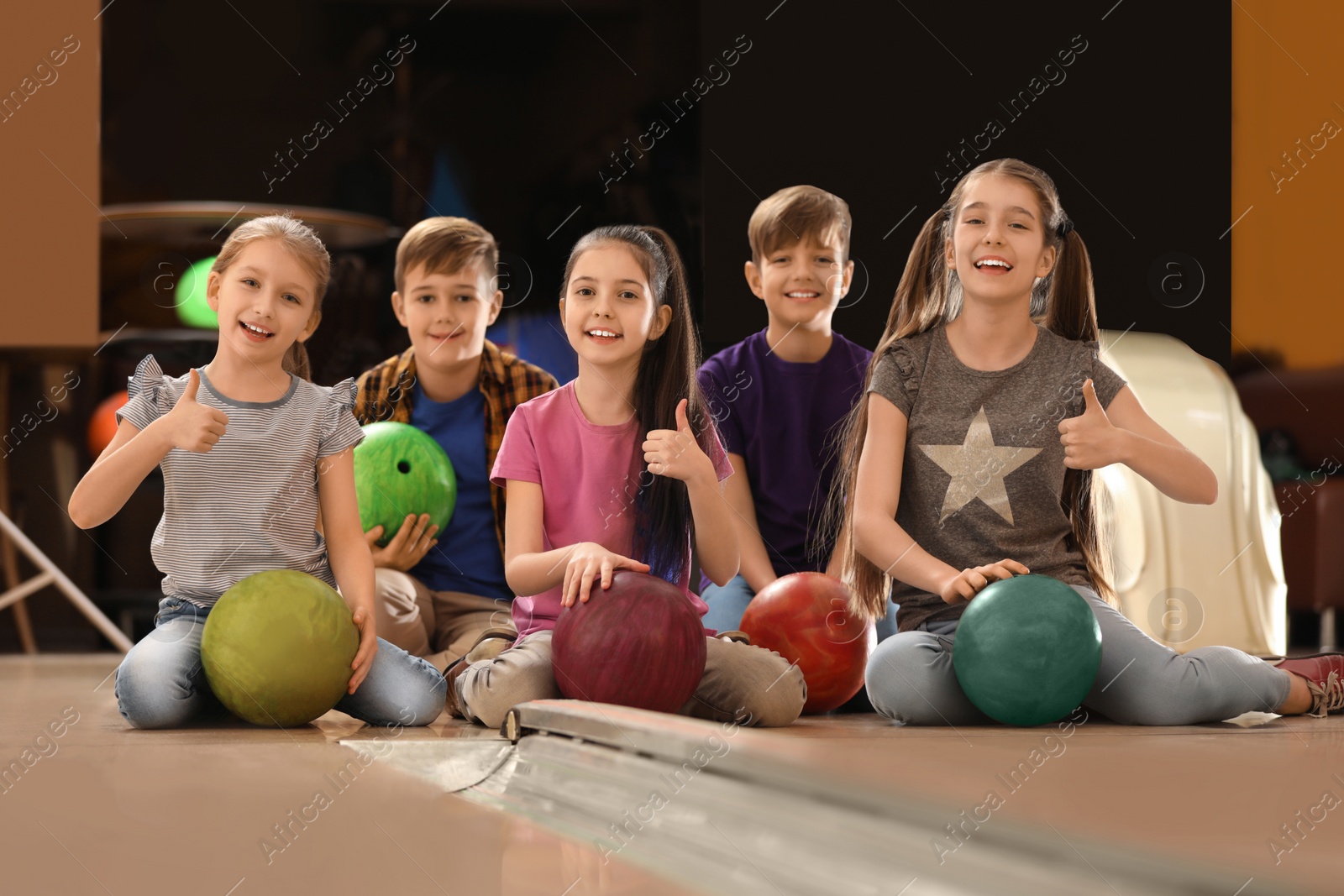 Photo of Happy children with balls in bowling club