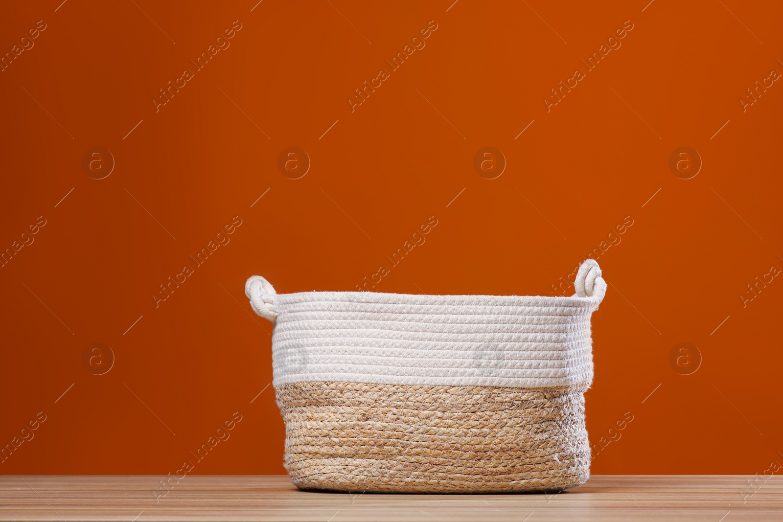 Photo of Empty wicker laundry basket near brown wall