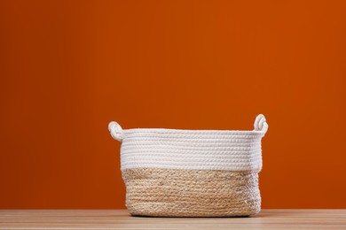 Photo of Empty wicker laundry basket near brown wall