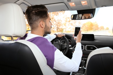 Young man using phone in driver's seat of modern car