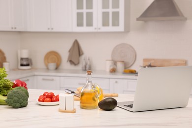 Set of tasty healthy products and laptop on table in kitchen. Online recipe