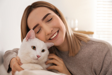 Photo of Young woman with her beautiful white cat at home. Fluffy pet