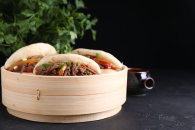 Delicious gua bao in bamboo steamer on black table