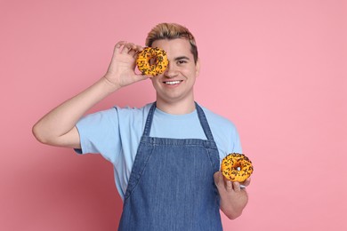 Photo of Portrait of happy confectioner holding donuts on pink background
