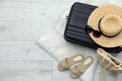 Photo of Suitcase and summer accessories on floor, flat lay. Space for text