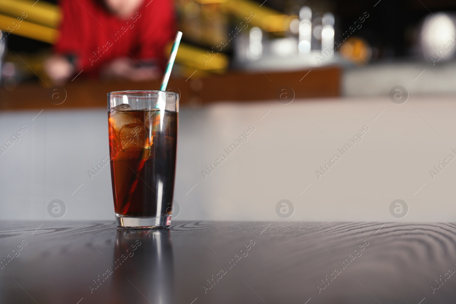 Photo of Glass of refreshing cola with ice on table indoors. Space for text