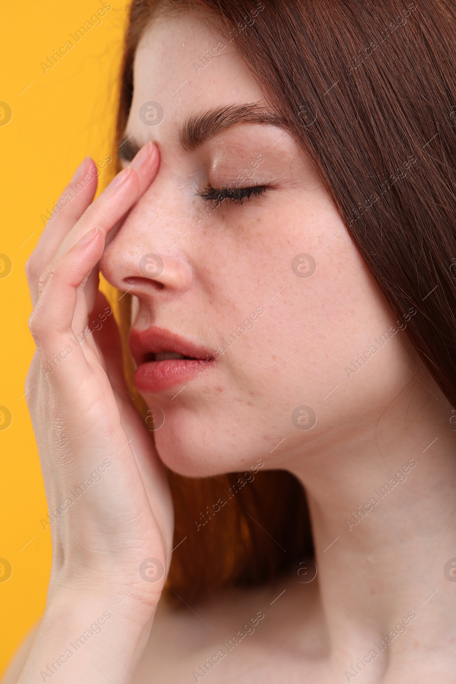 Photo of Portrait of beautiful woman with freckles on yellow background, closeup