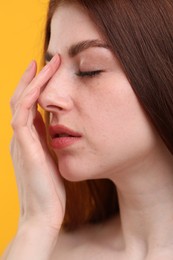 Portrait of beautiful woman with freckles on yellow background, closeup