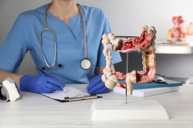 Photo of Gastroenterologist with human colon model at table in clinic, closeup