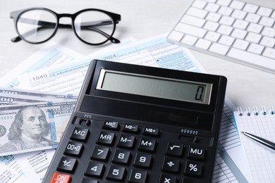Tax accounting. Calculator, documents, money, stationery and glasses on light grey table, closeup