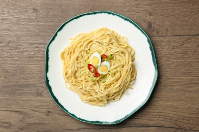 Plate of tasty noodles on wooden background, top view