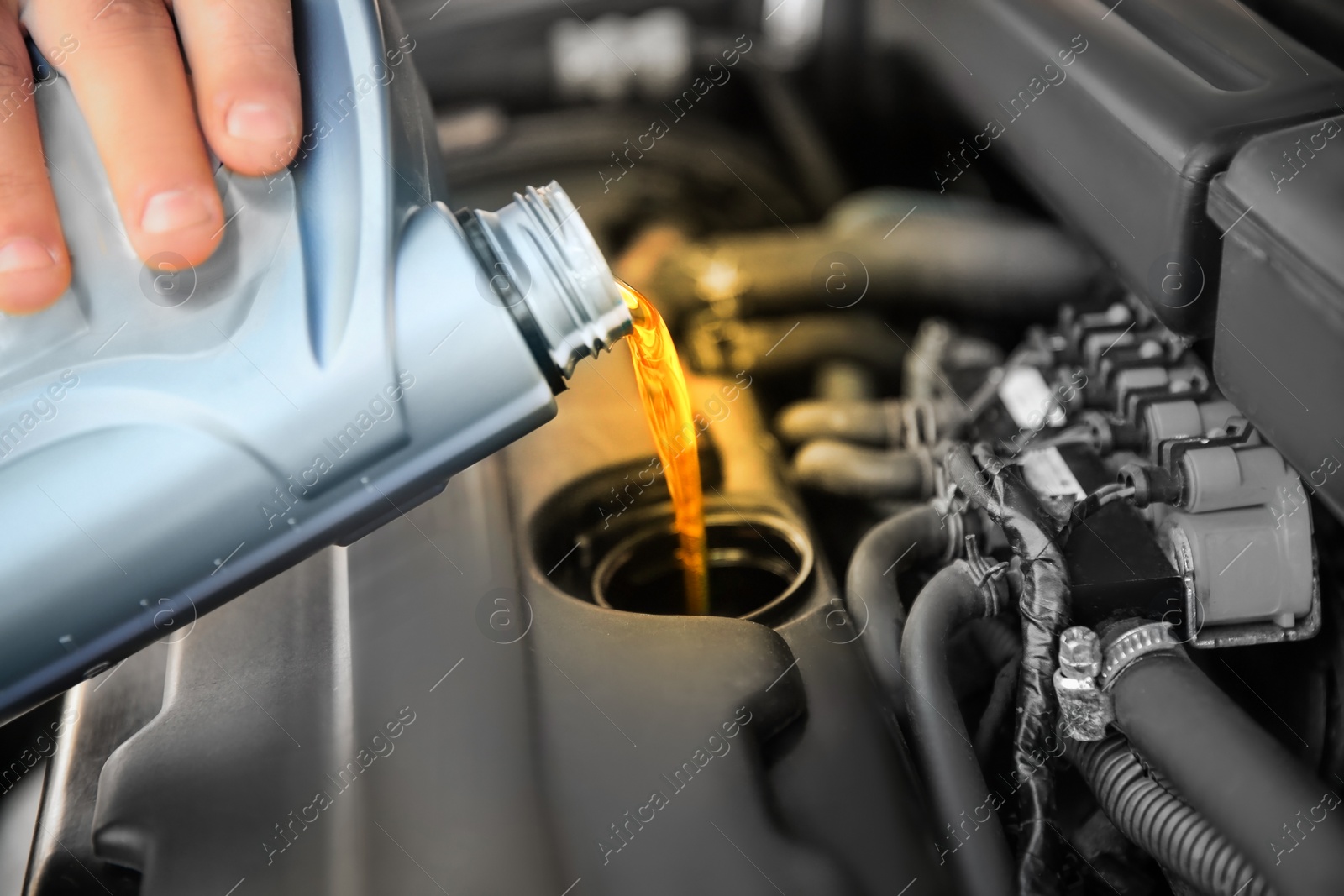 Image of Man pouring motor oil into car engine, closeup. Color accent effect