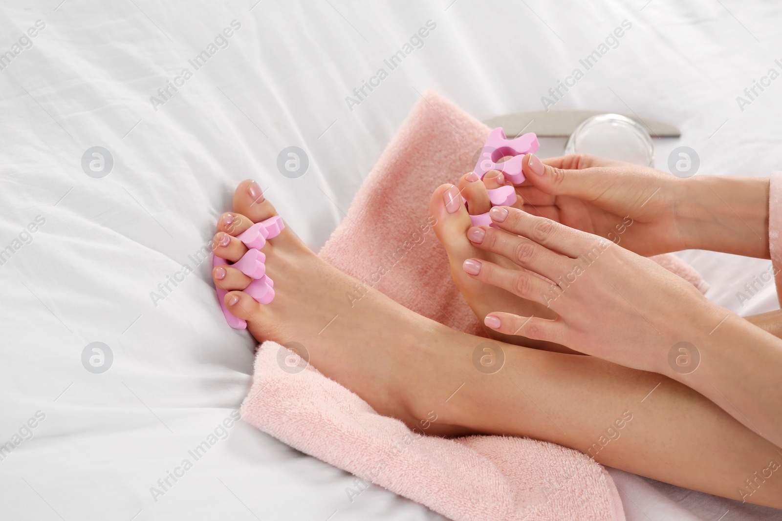 Photo of Woman preparing toenails for pedicure on bed at home, closeup