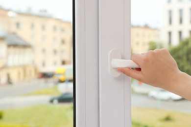 Photo of Woman opening white plastic window at home, closeup