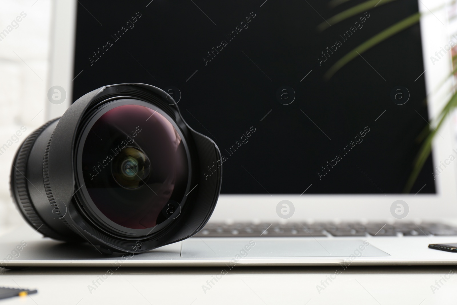 Photo of Camera lens on laptop, closeup. Professional photographer's equipment