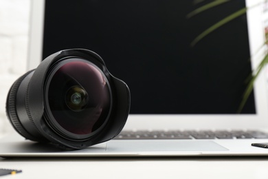 Photo of Camera lens on laptop, closeup. Professional photographer's equipment