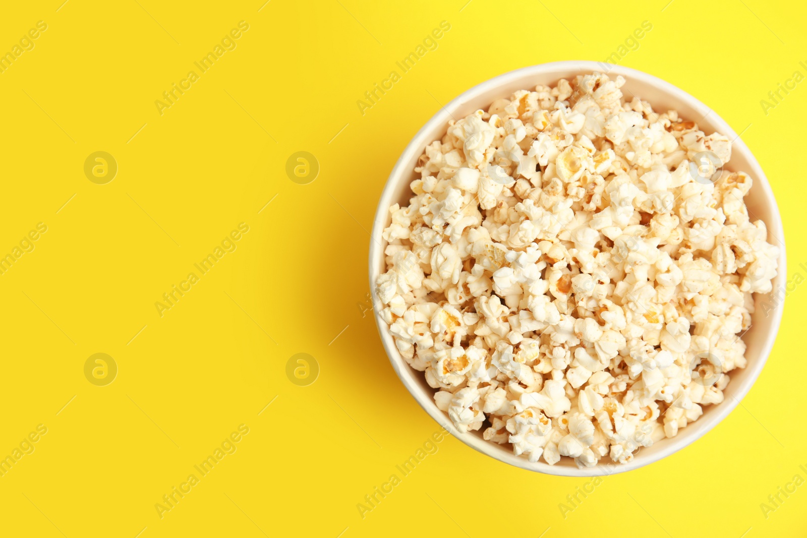 Photo of Tasty pop corn on yellow background, top view. Space for text