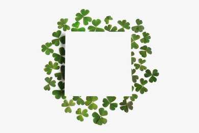 Green clover leaves and blank card on white background, flat lay