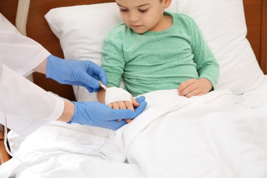 Photo of Doctor adjusting intravenous drip for little child in hospital