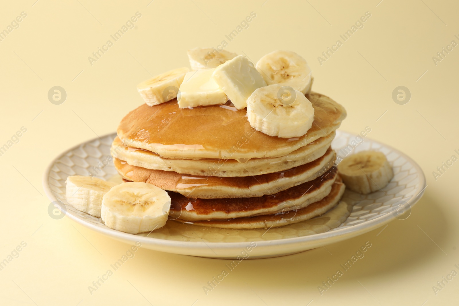 Photo of Delicious pancakes with bananas, honey and butter on beige background, closeup