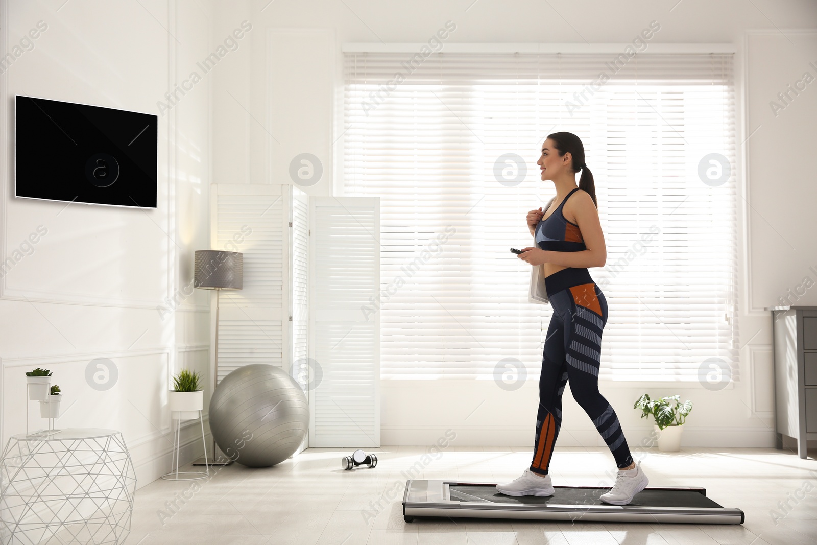 Photo of Sporty woman training on walking treadmill at home