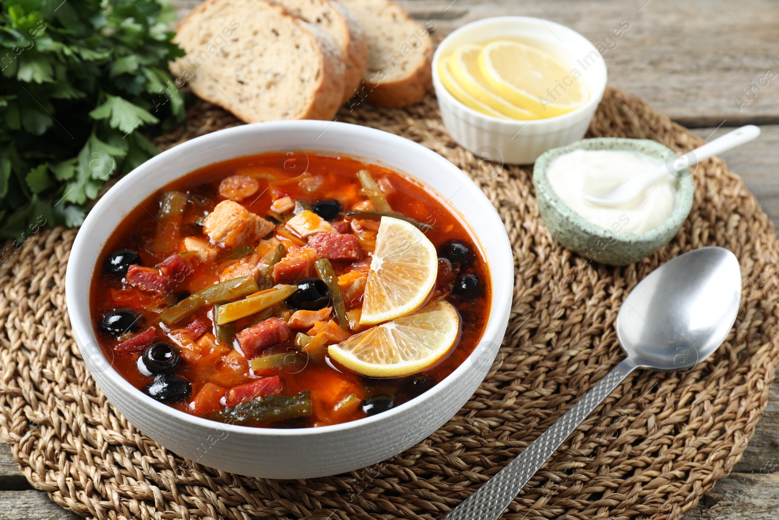 Photo of Meat solyanka soup with sausages, olives and vegetables served on table