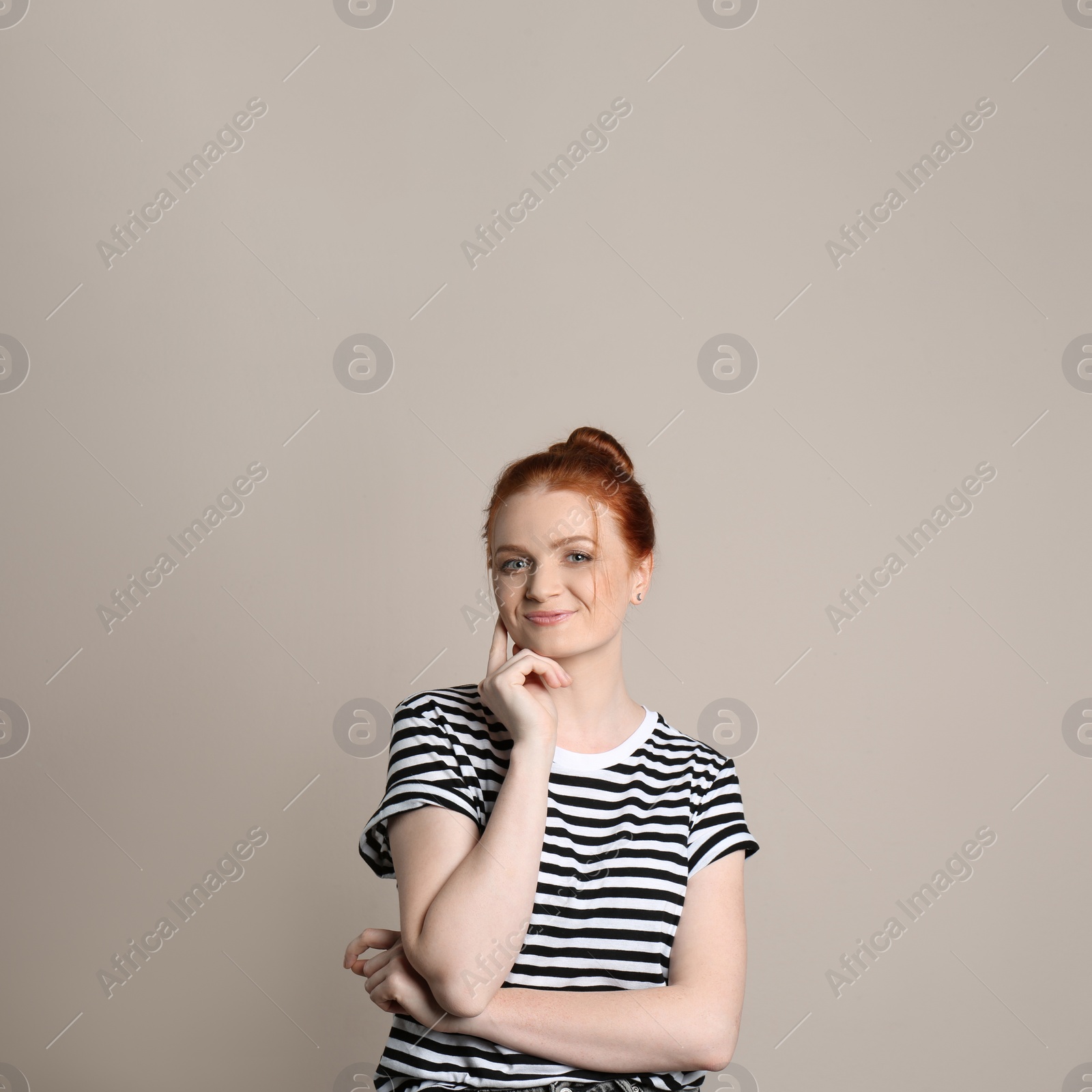 Photo of Candid portrait of happy red haired woman with charming smile on beige background