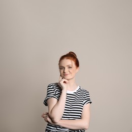Photo of Candid portrait of happy red haired woman with charming smile on beige background