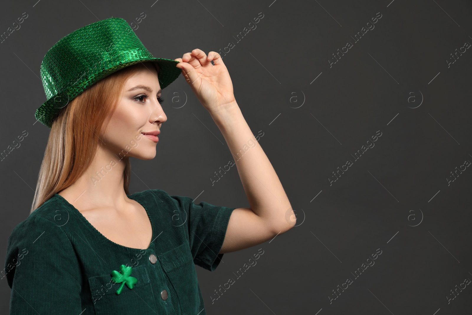 Photo of Young woman in green outfit on grey background, space for text. St. Patrick's Day celebration