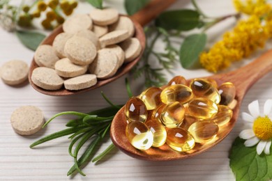 Different pills, herbs and flowers on white wooden table, closeup. Dietary supplements