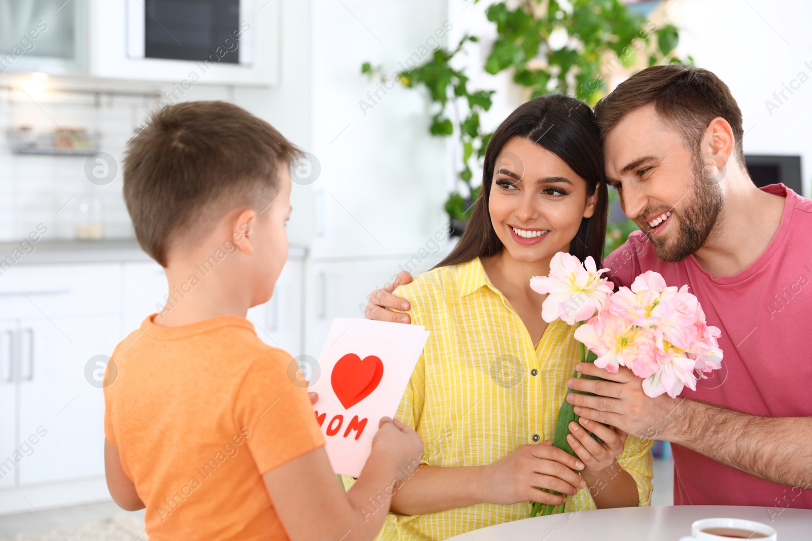 Photo of Father and son congratulating mom in kitchen. Happy Mother's Day