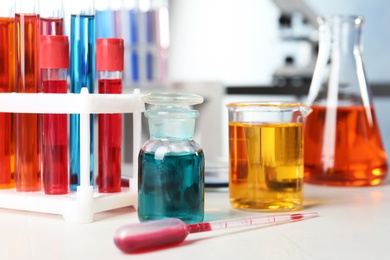 Photo of Different glassware with samples on table in chemistry laboratory