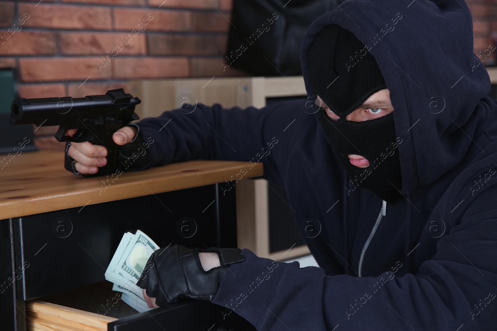 Photo of Dangerous masked criminal with gun stealing money from house