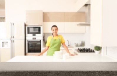 Happy woman with clean dishes in kitchen, focus on empty table